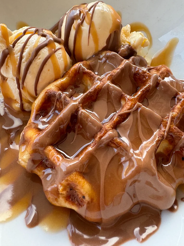 Belgian waffle covered in melted Belgian chocolate with ice cream