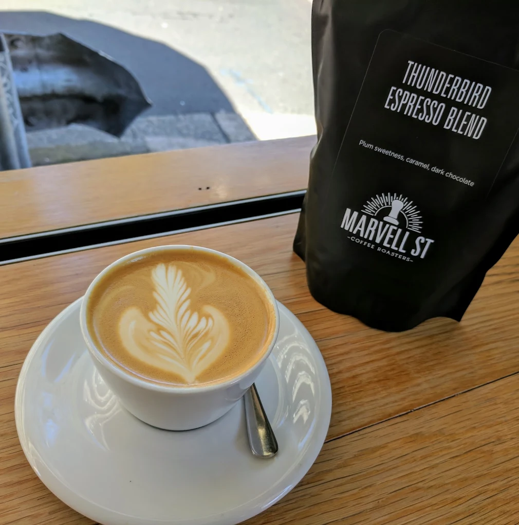 Flat white with latte art beside a bag of Thunderbird espresso beans