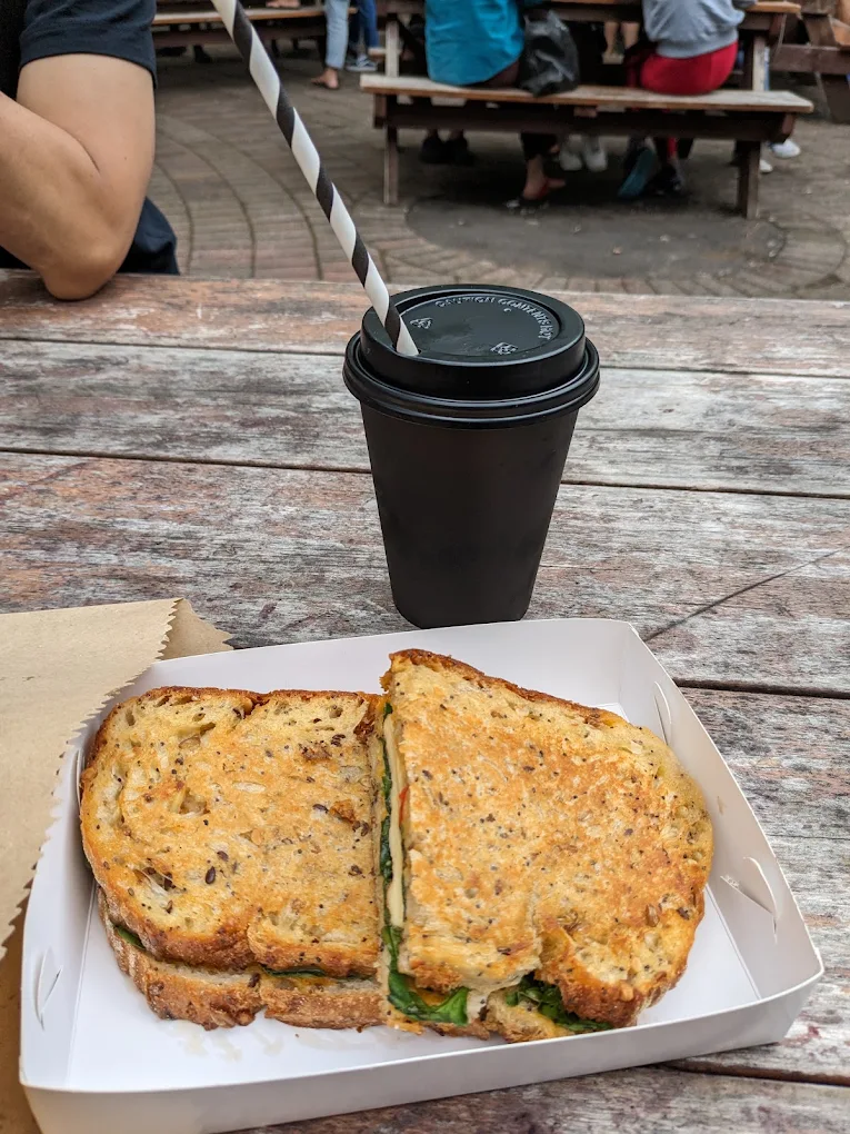 Takeaway flat white and a toastie on a picnic table