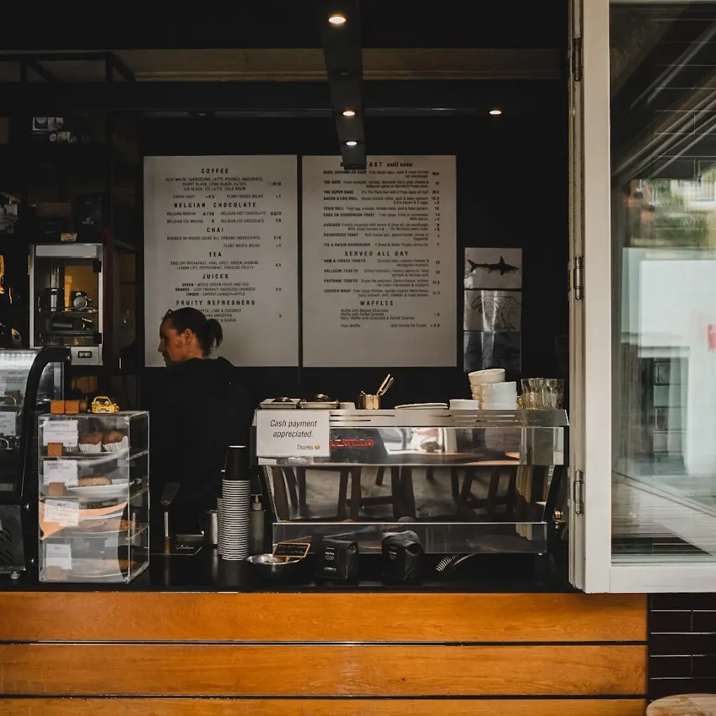 Barista working behind the counter beneath the menu board